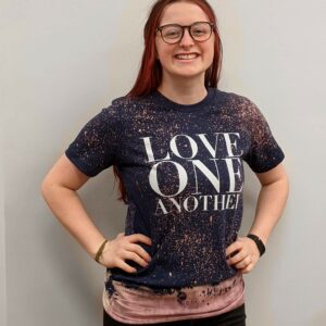 Women modeling t shirt with saying love one another in white