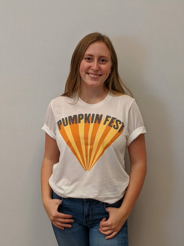 women wearing white t shirt with pumpkin feast logo in gray, yellow and orange on front
